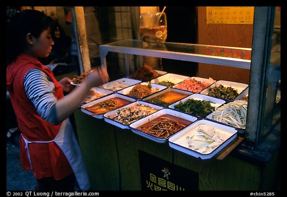 Woman helping herself to food. Sichuan food is among China's spiciest. Chengdu, Sichuan, China (color)