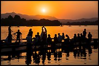 Couple embracing at sunset among crowd, West Lake. Hangzhou, China
