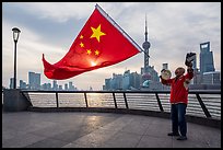 Man saluting Chinese flag and skyline, the Bund. Shanghai, China ( color)