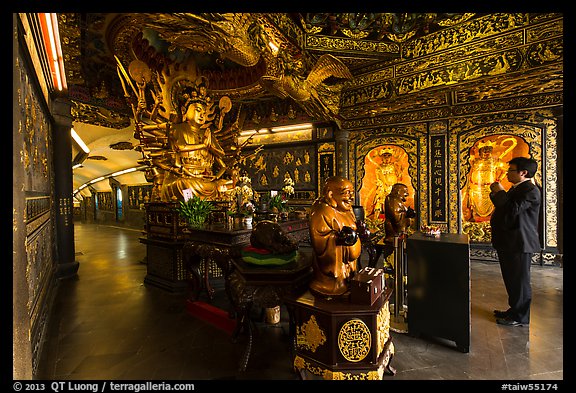 Tourist praying at tunnel entrance, Guandu Temple. Taipei, Taiwan