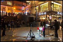 Tourists watch girl singing at night near the pier, Shueishe Village. Sun Moon Lake, Taiwan (color)