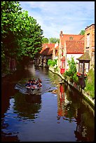 Boat on a canal lined with houses and trees. Bruges, Belgium (color)