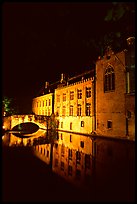 Houses and bridge reflected in canal at night. Bruges, Belgium