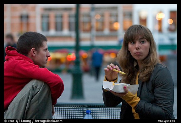 Young woman eating fries, Markt. Bruges, Belgium (color)