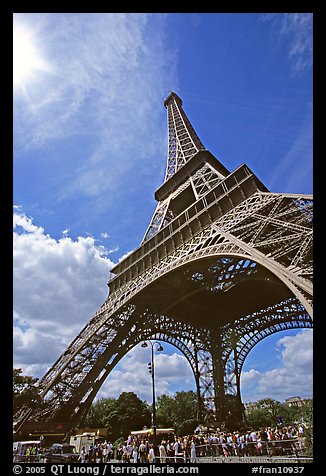 Eiffel tower and sun with crowds at base. Paris, France