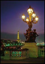 Bronze lamp post with scultpure on Pont Alexandre III, and Eiffel Tower at night. Paris, France (color)