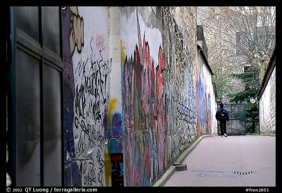 Boy in side alley with graffiti on walls. Paris, France