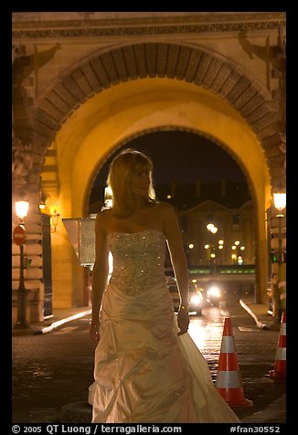 Woman in bridal gown in front of the Louvre by night. Paris, France