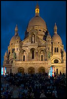 Tourists sitting on the stairs of the Sacre coeur basilic in Montmartre at night. Paris, France (color)