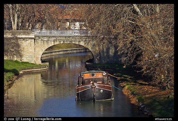 Tranquil scene with barge, bridge, and trees, Canal du Midi. Carcassonne, France