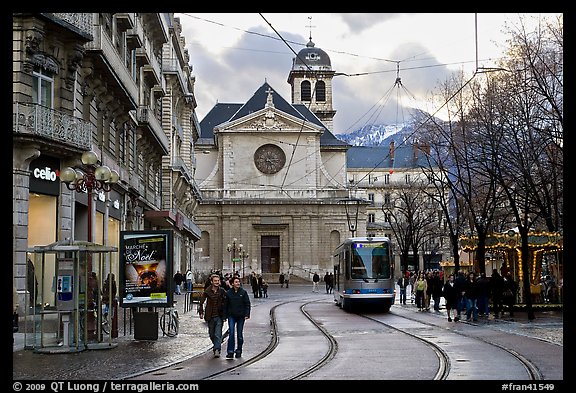 Street with people walking, tramway and church. Grenoble, France