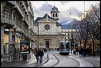 Street with people walking, tramway and church. Grenoble, France