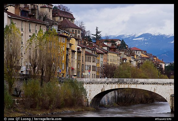 Stone bridge, houses, and snowy mountains. Grenoble, France