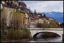 Stone bridge, houses, and snowy mountains. Grenoble, France