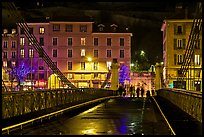 Pedestrians on suspension bridge at night. Grenoble, France