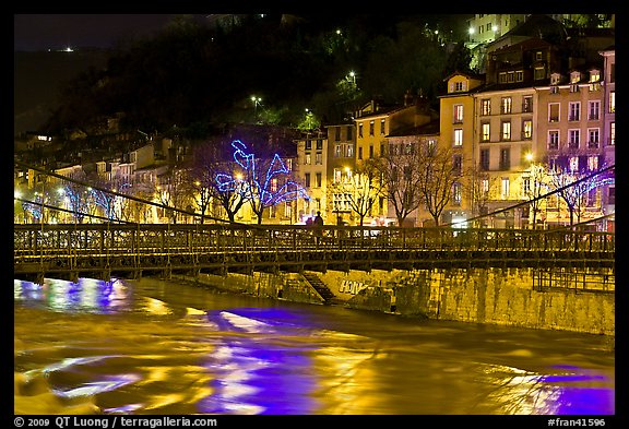 Suspension bridge at night with Christmas lights reflected in river. Grenoble, France (color)