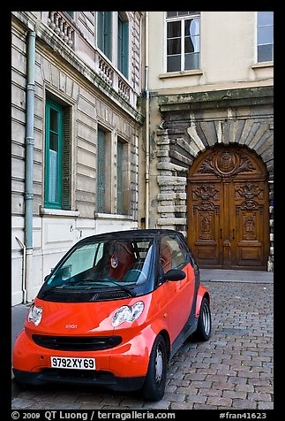 Tiny car on coblestone pavement in front of historic house. Lyon, France