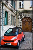 Tiny car on coblestone pavement in front of historic house. Lyon, France (color)