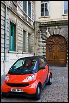 Tiny car on coblestone pavement in front of historic house. Lyon, France