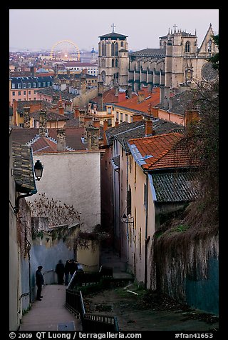 Stairs, rooftops, St-Jean Cathedral, and Ferris Wheel at dusk. Lyon, France