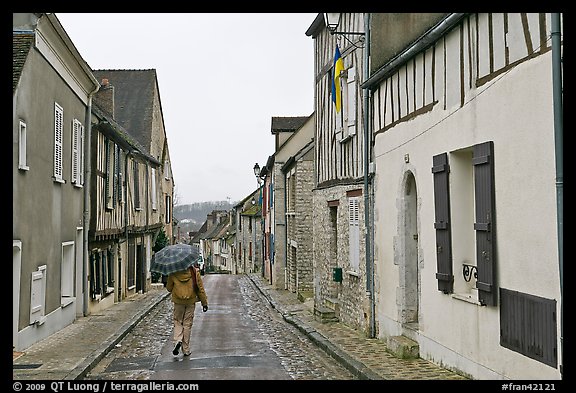 Pedestrian with umbrella in narrow street, Provins. France (color)