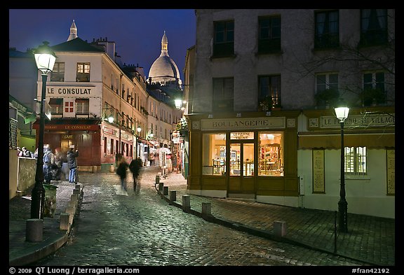 Cobblestone street, lamps, and Sacre-Coeur basilica by night, Montmartre. Paris, France