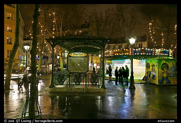 Square with subway entrance and carousel by night. Paris, France