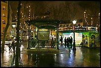 Square with subway entrance and carousel by night. Paris, France