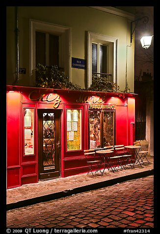 Restaurant with red facade and cobblestone street by night, Montmartre. Paris, France