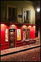 Restaurant with red facade and cobblestone street by night, Montmartre. Paris, France ( color)