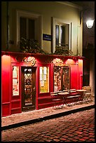 Restaurant with red facade and cobblestone street by night, Montmartre. Paris, France (color)