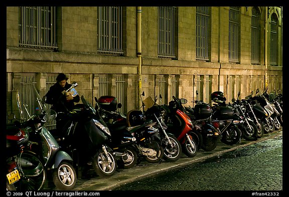 Scooters parked on a sidewalk at night. Paris, France (color)