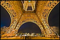 Eiffel Tower pilars from below and Ecole Militaire at night. Paris, France