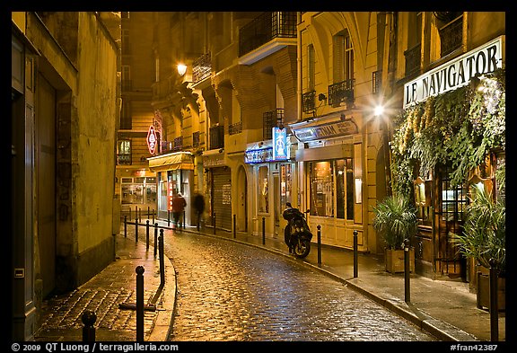 Street with cobblestone pavement and restaurants by night. Quartier Latin, Paris, France