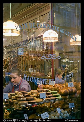 Woman selling pastries and bread in bakery. Paris, France