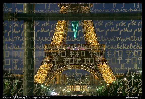 Lit Eiffel Tower seen through the words Peace written in many languages. Paris, France