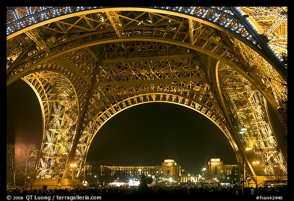 Palais de Chaillot seen through the base of Eiffel Tower by night. Paris, France