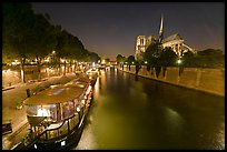 Quay, lighted boats, Seine River and Notre Dame at night. Paris, France