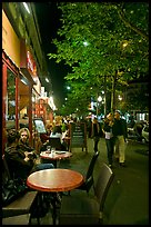 Couple walking by outdoor tables of cafe at night. Paris, France ( color)