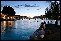 People sitting on tip of Ile de la Cite at sunset. Paris, France