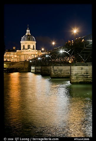 Institut de France and Pont des Arts reflected in Seine river at night. Paris, France