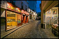 Narrow cobblestone street and businesses at night, Montmartre. Paris, France ( color)