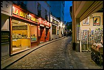 Narrow cobblestone street and businesses at night, Montmartre. Paris, France (color)