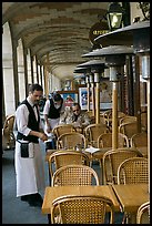 Waiters and customer, place des Vosges arcades. Paris, France