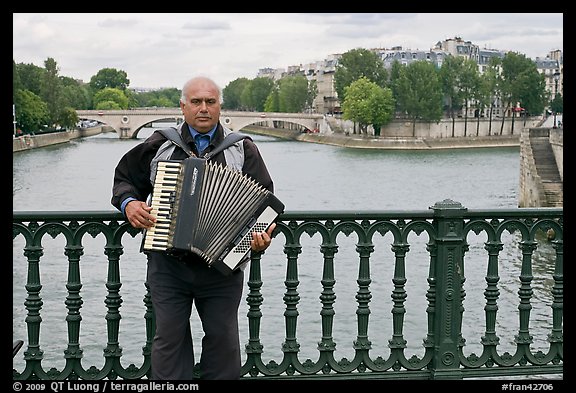 Street musician playing accordeon on River Seine bridge. Paris, France (color)