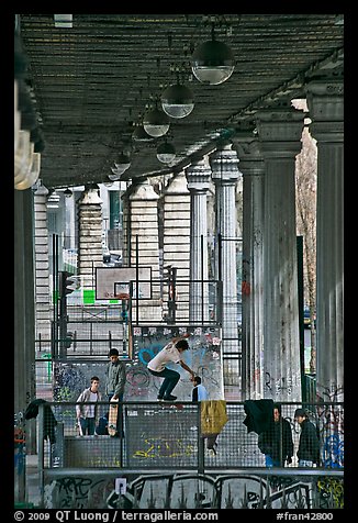 Youngsters skateboarding below metro bridge. Paris, France