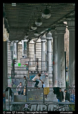 Youngsters skateboarding below metro bridge. Paris, France (color)