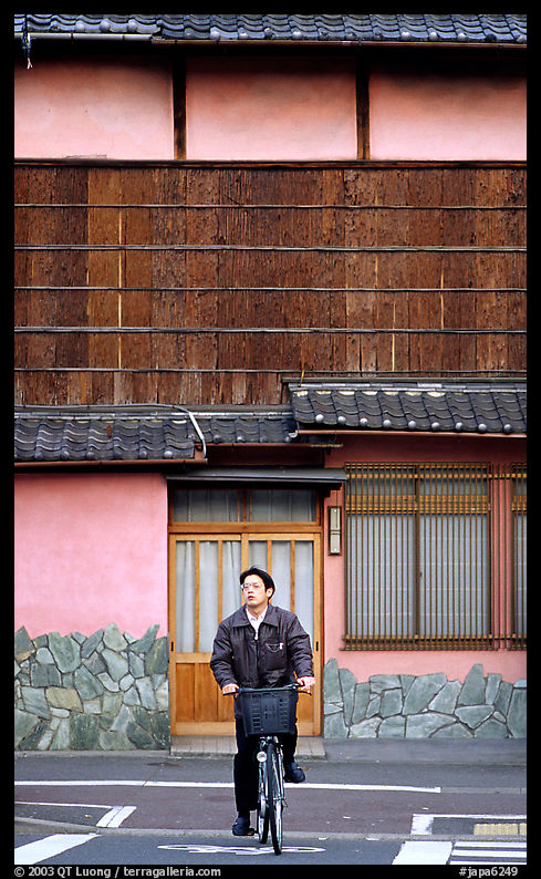 Bicyclist in front of a traditional style house. Kyoto, Japan
