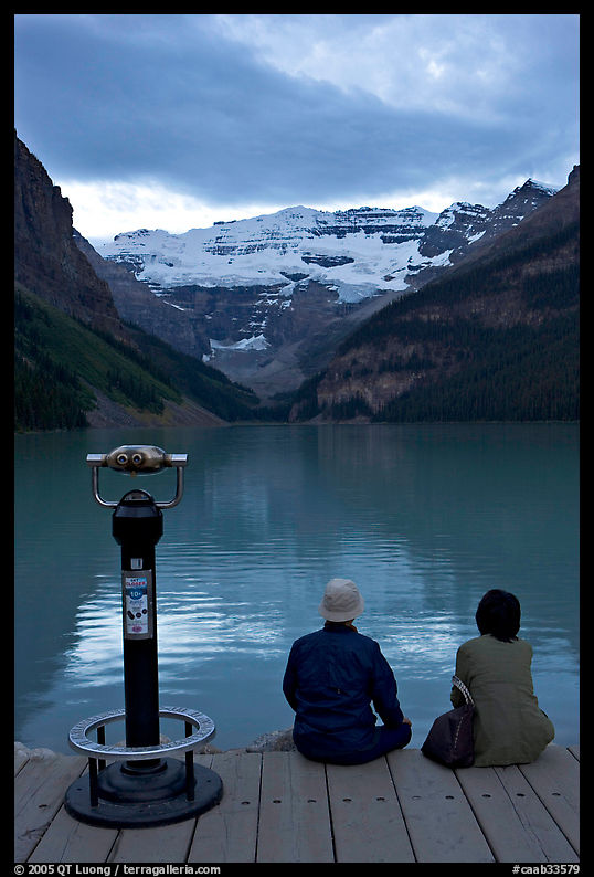 Couple sitting at the edge of Lake Louise at dawn. Banff National Park, Canadian Rockies, Alberta, Canada