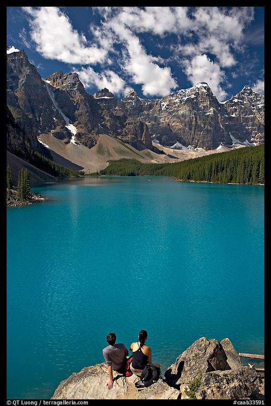 Couple sitting on the edge of Moraine Lake. Banff National Park, Canadian Rockies, Alberta, Canada